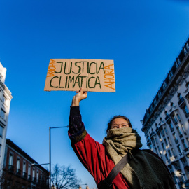 Una mujer sujeta una pancarta durante una manifestación del movimiento ‘Juventud por el Clima’, frente al Congreso de los Diputados, a 3 de marzo de 2023, en Madrid.