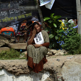 Un familiar de uno de los fallecidos por el derrumbe, en el lugar donde se encontraba el edificio. - AFP
