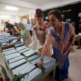 Dos mujeres vestidas de flamenca eligen sus papeletas en un colegio de Córdoba donde se está celebrado la Feria de Nuestra Señora de la Salud. EFE