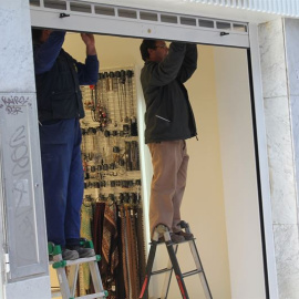 Trabajadores mueven la persiana de un comercio. EP