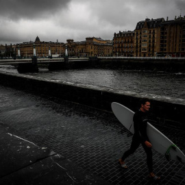 27/05/2019 - Un surfista camina junto al río Urumea este lunes en San Sebastián, donde las precipitaciones no han cesado en todo el día y se prevé que la situación no cambie hasta el jueves | EFE/ Javier Etxezarreta