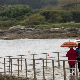Dos personas caminan con paraguas en la localidad de San Cibrao, Lugo, a 25 de abril de 2023.