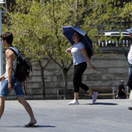Una mujer se protege con un paraguas del calor en Bilbao, donde los valores registrados este viernes se sitúan entre 10 y 15 grados por encima de lo normal en el noroeste peninsular. | EFE