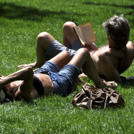 Dos personas descansan en el parque de El Retiro, en Madrid, en una jornada en la que la llegada del viento subsahariano a la Península "instalará el verano" en casi toda España, especialmente en Andalucía, Extremadura y área del Mediterrán