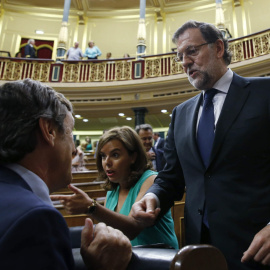 El presidente del Gobierno, Mariano Rajoy, conversa con el portavoz parlamentario del PP, Rafael Hernando, en presencia de la vicepresidenta, Soraya Sáenz de Santamaría, tras finalizar la votación en la que se rechazaron todas las enmiendas