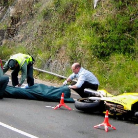 Miembros de la Guardia Civil de Tráfico y del servicio de emergencias se disponen al traslado de una de las tres víctimas mortales, tres motoristas, que fallecieron hoy en el accidente de tráfico registrado en el kilómetro 16 de la carreter