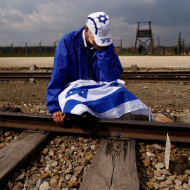 Un hombre sentado junto a las vías del tren del campo de concentración nazi de Auschwitz-Birkenau. REUTERS/Kacper Pempel