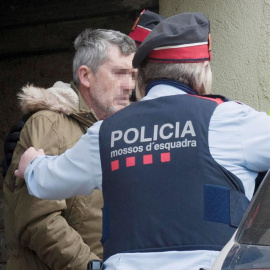 El presunto autor del doble homicidio de Susqueda, Jordi Magentí (i), acompañado de los mosos d'esquadra en el momento de acceder a una casa de Anglès. /EFE