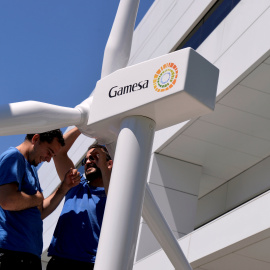 Dos operarios con la maqueta de un aerogenerador en la entrada de la sede de Gamesa, en Zamudio. REUTERS