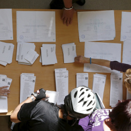 Varias personas escogen su papeleta para las elecciones al Parlamente de este 27-S en una mesa de un colegio electoral de Barcelona. REUTERS/Albert Gea