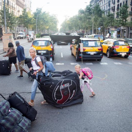 31/07/2018.- Unos turistas llevan sus maletas mientras los taxistas mantienen las concentraciones en el centro de la ciudad con motivo de la huelga iniciada el pasado 25 de julio, por el conflicto de las licencias VTC (alquiler de vehículos