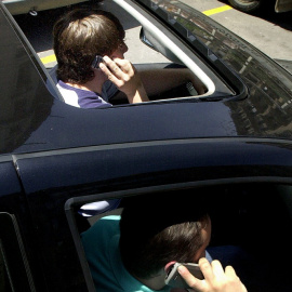 Foto de archivo de dos personas hablando por el móvil dentro de un coche. - EFE