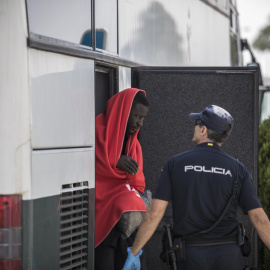 Un migrante baja del autobús de la Guardia Civil que le han trasladado del un pabellón cercano hasta el nuevo centros de atención para extranjeros habilitado en el puerto de Campamento (Cádiz).- JAIRO VARGAS