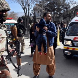 Un hombre sostiene a un niño ante un militar tras el ataque a una iglesia metodista en Pakistán. /EFE
