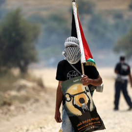 Un manifestante enmascarado sostiene una bandera palestina durante los enfrentamientos con soldados israelíes en una protesta delante del día de la Nakba , en la localidad cisjordana de Bilin cerca de Ramallah, 13 de mayo de 2016. REUTERS /