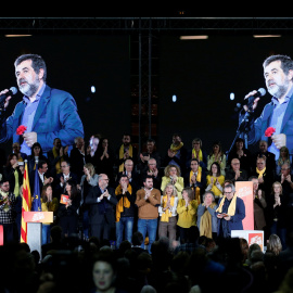 La imagen del presidente de ANC y número dos de la lista de Junts per Catalunya aparece en sendas pantallas mientras por megafonía suena una grabación de su voz, en un mitin de la candidatura soberanista en Barcelona. REUTERS/Albert Gea