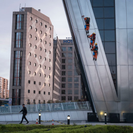Un policía camina debajo de los activistas de Greenpeace al inicio de la escalada. GREENPEACE.