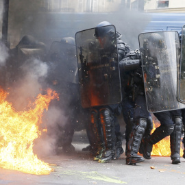 Gendarmes franceses, entre llamas provocadas por un grupo de encapuchados en París, durante las protestas contra la reforma laboral.- REUTERS
