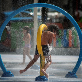 Una niña se refresca en los chorros del parque de la alameda de O Cruceiro en Ourense. / EFE