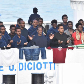 Migrantes rezan a la espera del desembarco del barco italiano de la Guardia Costera italiana en Catania. - EFE