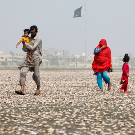 Una mujer se cubre el rostro con la bufanda para evitar el calor mientras camina con su familia por la playa en un día caluroso de verano en Karachi, Pakistán. REUTERS/Akhtar Soomro