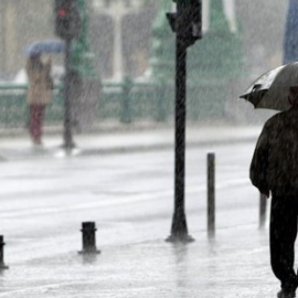 Foto de archivo de un hombre que camina bajo la lluvia en San Sebastián. / EFE