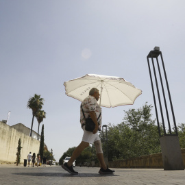 Un hombre se protege del sol con una sombrilla en una jornada de intenso calor.