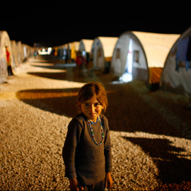 Una niña kurda sonríe a la cámara durante una noche en un campo de refugiados en la cuidad fronteriza de Suruc, provincia de Sanliurfa (Turkía). // OSMAN ORSAL (REUTERS)