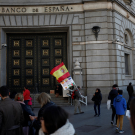 Un hombre con la bandera española y una pancarta junto a la sede del Banco de España en Barcelona. REUTERS/Jon Nazca