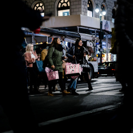 Dos personas cruzan la calle cargando bolsas a la salida de unos grandes almacenes en Nueva York./EFE