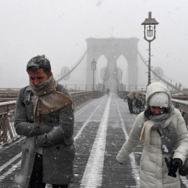 Varias personas caminan por el puente de Brooklyn, en Nueva York, en medio de la peor tormenta de la temporada en EEUU, que ha afectado a todo el noroeste del país.	REUTERS/Darren Ornitz