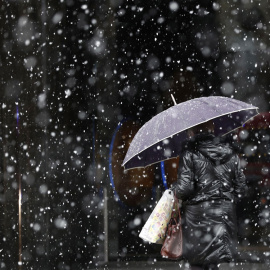 Una mujer camina bajo la nieve en Pamplona. EFE