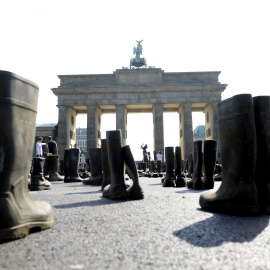 Activistas de la Federación de Ganaderos Alemanes (BDM) protestan rodeados de botas de goma en una manifestación contra el precio de la leche en la Puerta de Brandeburgo en Berlín, Alemania. EFE/Maurizio Gambarini