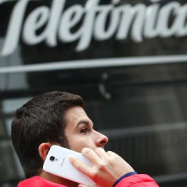 Un hombre habla por su móvil, delante de la sede de Telefónica en la madrileña Gran Vía. REUTERS