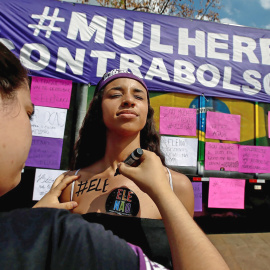 Una mujer pinta en la piel de otra: 'Él no', durante las manifestaciones contra Bolsonaro este sábado en Sao Paulo. REUTERS