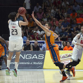 El alero del Real Madrid, Sergio Llul (i), lanza un triple a falta de 1,8 segundos de la prórroga, consiguiendo la victoria ante el Valencia Basket. /EFE