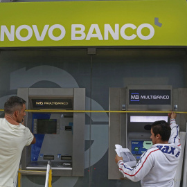 Dos operarios cambian el rótulo de una oficina del BES por su nuevo nombre Novo Banco. REUTERS
