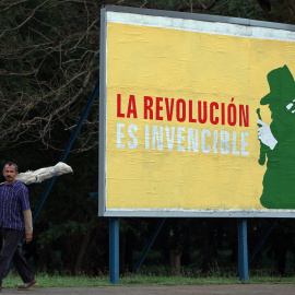 Un hombre camina junto a un cartel alusivo a la revolución cubana, en una calle de La Habana (Cuba). EFE/Alejandro Ernesto