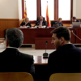 Lionel Messi junto a su padre en el banquillo para declarar por fraude fiscal. REUTERS/Alberto Estevez