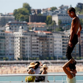 Unos jóvenes practican acrobacias junto a la playa de la Concha de San Sebastián / EFE - JUAN HERRERO