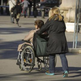 Una mujer mayor pasea con su cuidadora. EFE