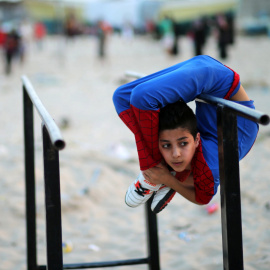 Mohamad al-Sheikh, un niño contorsionista palestino de 12 años, apodado Spiderman intenta lograr el récord Guinnes del mundo con sus demonstraciones acrobáticas y contorsionistas en una playa de Gaza. REUTERS/Mohammed Salem