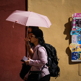 Varias personas pasean por la judería de Córdoba, protegidas por un paraguas del sol, a 29/09/2023.