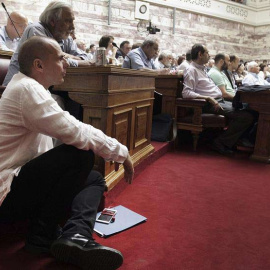 El ministro de Finanzas, Yannis Varufakis, escucha a Tsipras, ayer, martes, en el parlamento griego./ EFE