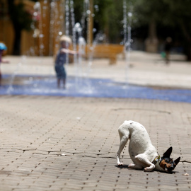Un perro se frota contra el pavimento tras mojarse en una fuente durante un caluroso día en Sevilla, España.REUTERS/Marcelo del Pozo