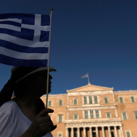Una manifestante sostiene una bandera griega en frente del Parlamento.-Yannis Kolesidis (EFE)