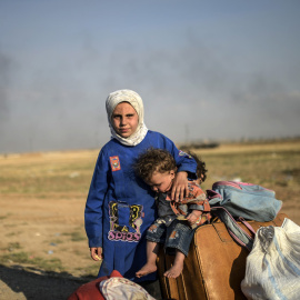 Niños sirios esperan con sus pertenencias tras pasar la frontera turca. AFP