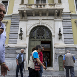 Varias personas pasan junto a la sede del Banco Nacional, en Atenas. REUTERS/Marko Djurica