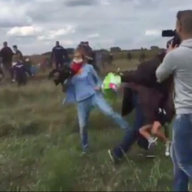 Petra László pone la zancadilla a un refugiado que corre con un niño en brazos en Röszke (Hungría).