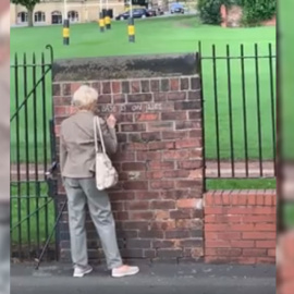 Captura del vídeo donde la mujer escribe en un muro con una tiza.